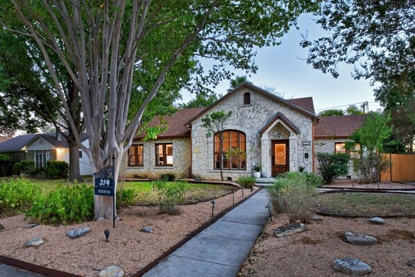 A stone house with a stone facade, a front porch, and a well-maintained garden with a pathway leading to the entrance. - San Antonio Resort Home | Pool, Hot Tub, Casita & Game Room (San Antonio)