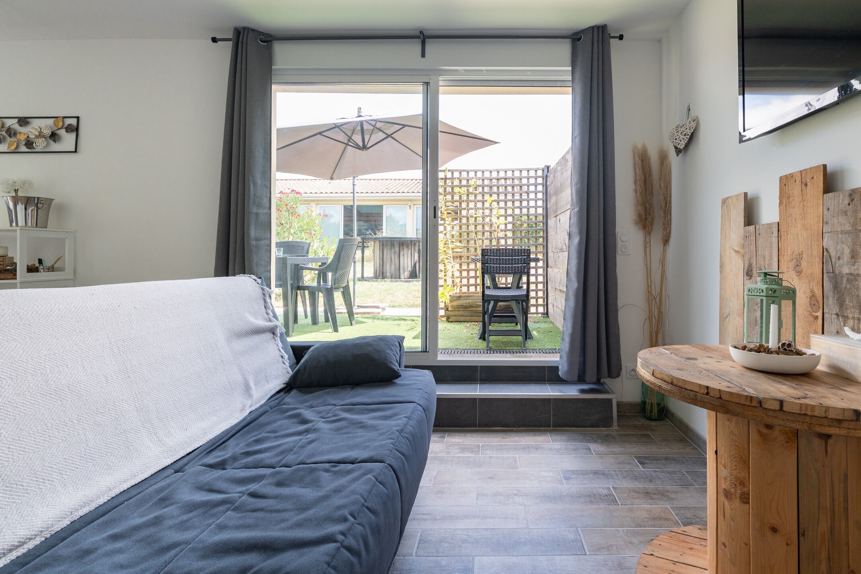 A bedroom with a bed, a wooden table, and a view of the outside.