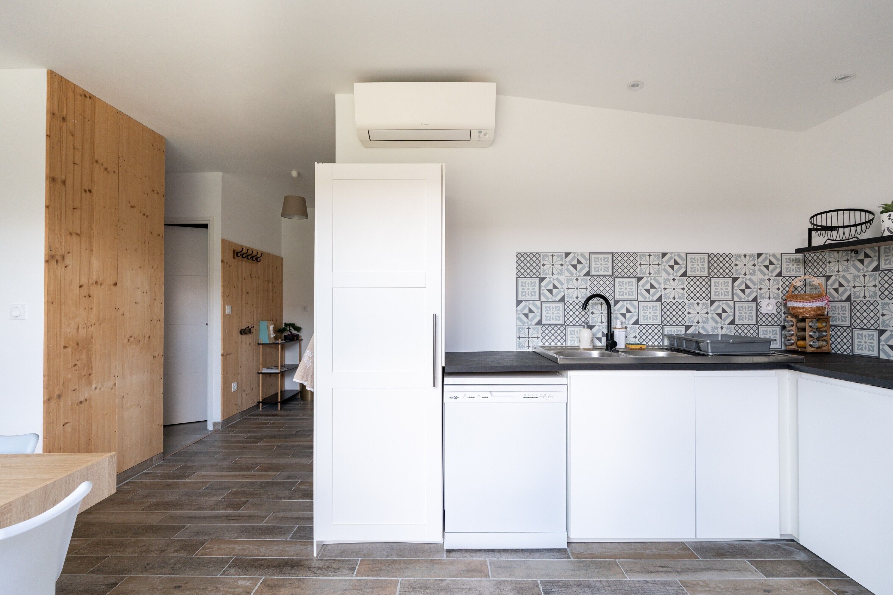 Een moderne keuken met witte kastjes, een vaatwasser en een betegelde achterwand.