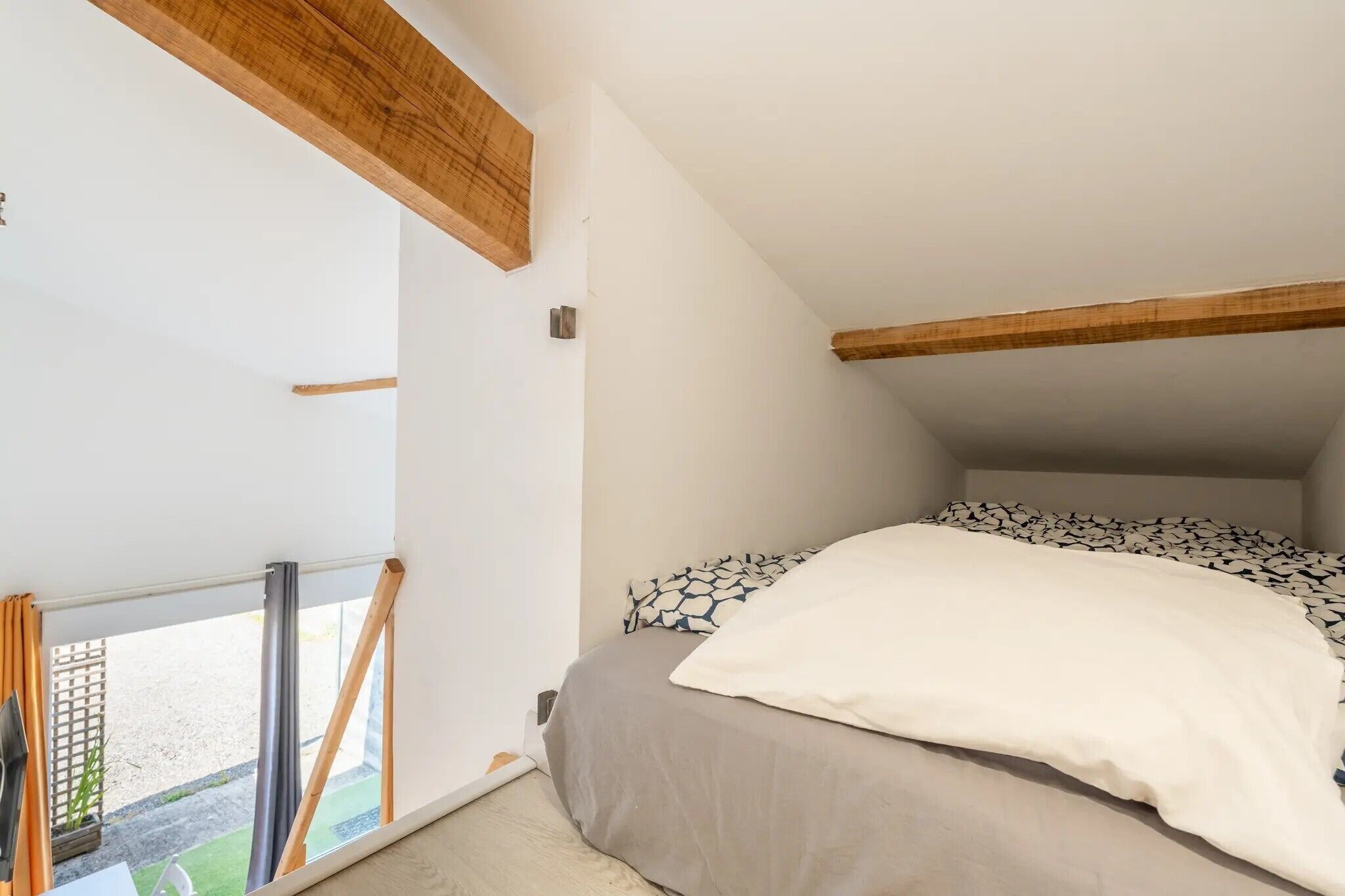 Een slaapkamer met een bed, een raam en een balkon.