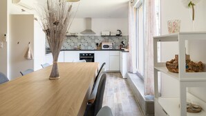 Eine moderne Küche mit weißen Schränken, einem Holztisch und einer Vase mit Trockenpflanzen.