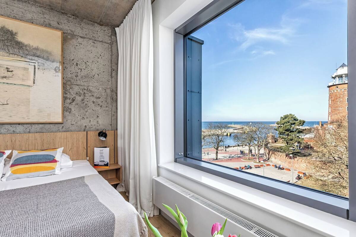 A hotel room with a large window offering a view of a historic building and a body of water.