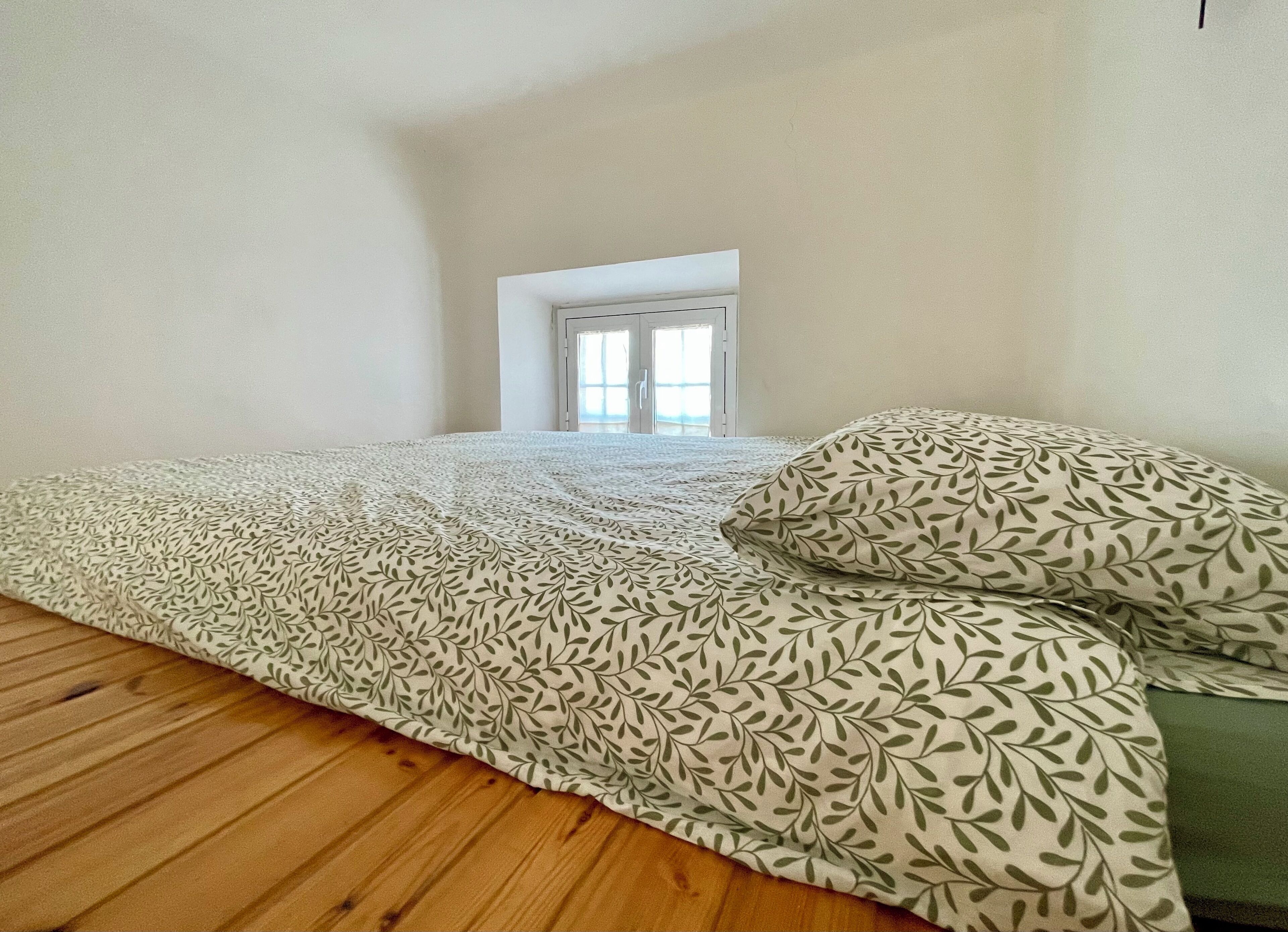 Ein Schlafzimmer mit einem Bett, einem Fenster und Holzboden.