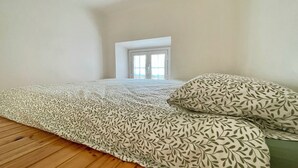 Une chambre à coucher avec un lit, une fenêtre et un plancher en bois.
