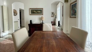 Un vaste espace dédié à la salle à manger, avec une table en bois, des chaises blanches et une lampe décorative.