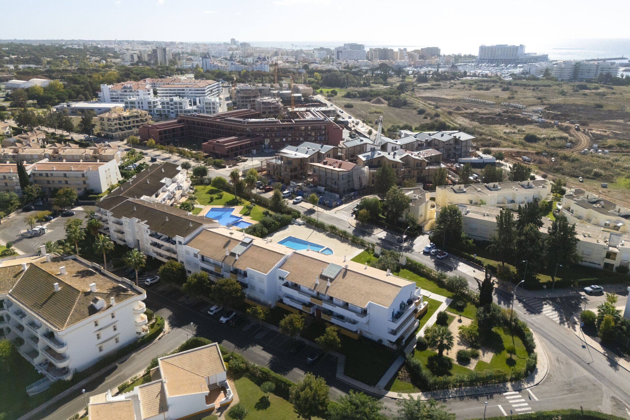 An aerial view of a residential area with multiple buildings, including a large complex with a swimming pool and several smaller structures.
