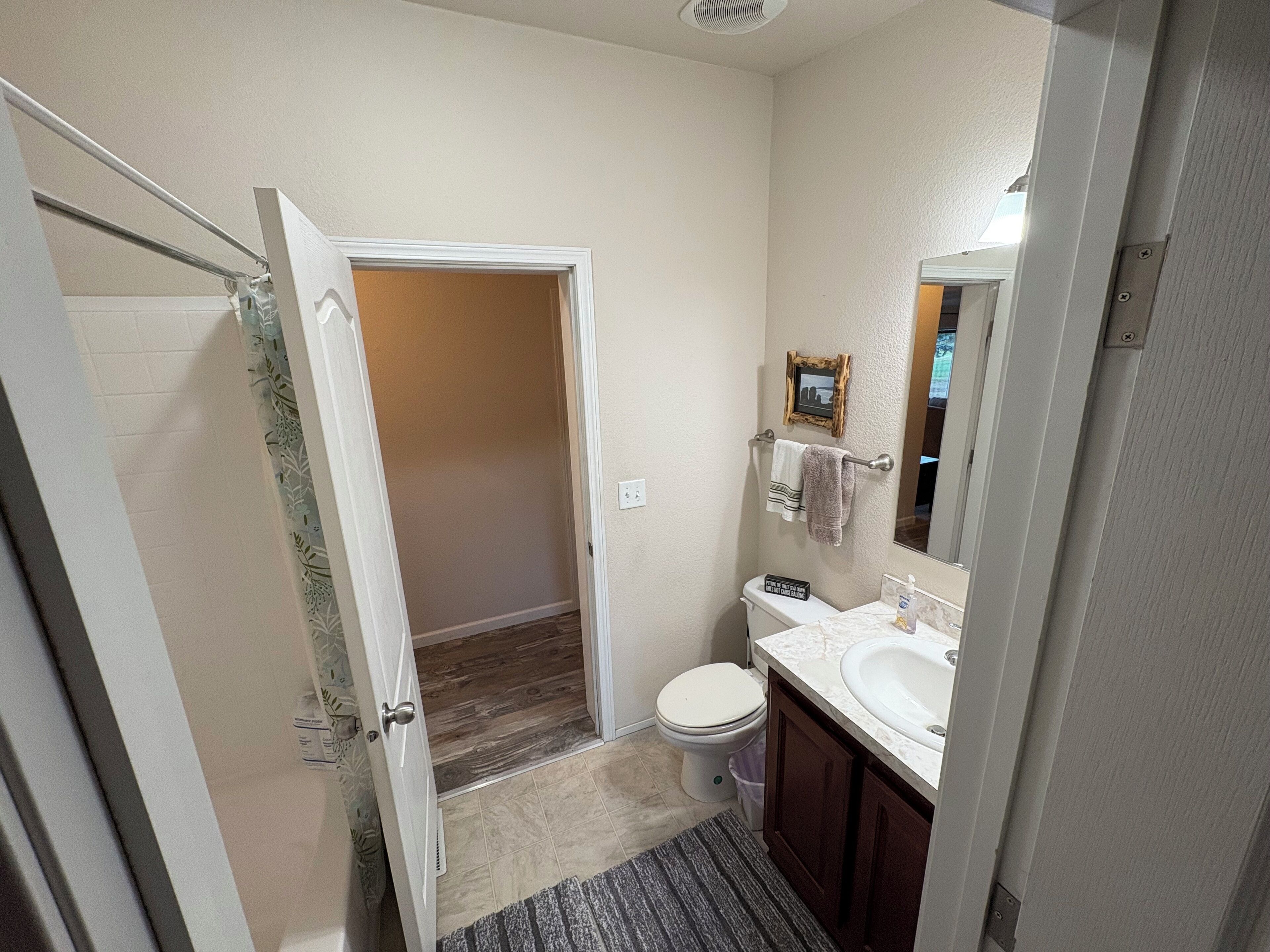 A bathroom with a toilet, sink, and mirror.