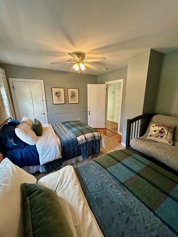 Ein Schlafzimmer mit einem Bett, einem Sessel, einem Deckenventilator und zwei Türen.