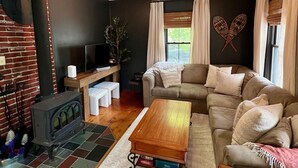 Un salón acogedor con chimenea, un sofá, una mesa de centro y un televisor.