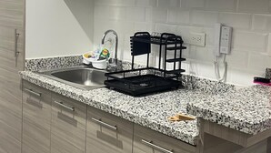 Eine moderne Küche mit einer Granitabdeckung, einer Edelstahlspüle und weißen Schränken.