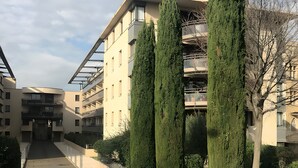 A multi-story building with a central staircase, surrounded by well-maintained greenery and tall cypress trees. - De Standing Avignon Apartment with Wi-Fi and Air Conditioning (Avignon)
