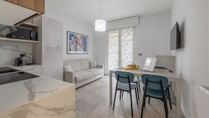 Una cocina moderna con microondas integrado, un comedor con dos sillas, una mesa y una lámpara colgante.