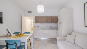 Una cocina moderna con armarios blancos, encimera de mármol y una lámpara colgante.