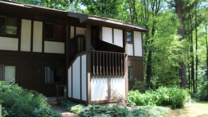 Ein zweigeschossiges Haus mit Balkon, umgeben von üppiger Vegetation und einem Pflasterweg.