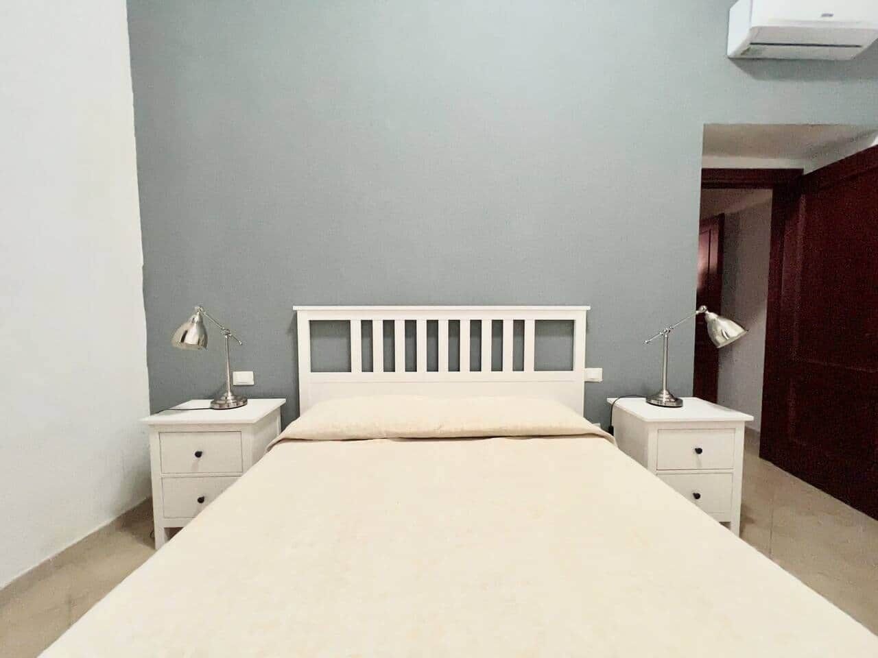 Ein Schlafzimmer mit einem Bett, zwei Nachttischen und einer Wand-Klimaanlage.