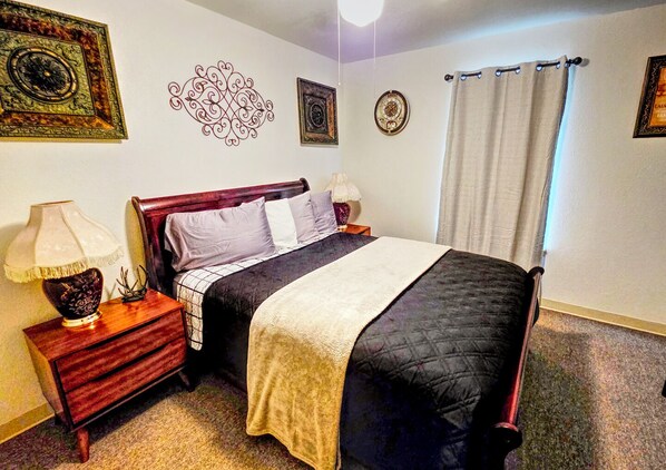 Un dormitorio ordenado con cama, mesitas de noche y decoración en la pared.