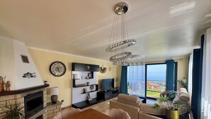Una sala de estar moderna con chimenea, una mesa de comedor y vista al mar.