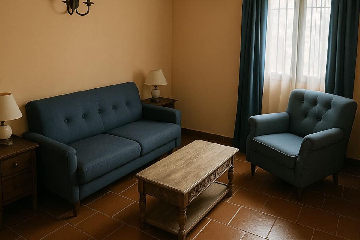 Una sala de estar con un sofá azul, un sillón a juego, una mesa de centro de madera y un aire acondicionado instalado en la pared.
