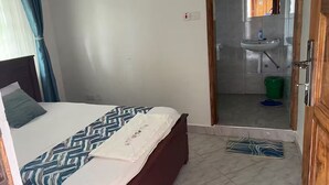 Un dormitorio con una cama, un baño visible a través de una puerta abierta y una alfombra pequeña en el suelo.