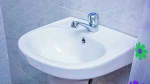 Un lavabo blanc pour la salle de bain, doté d’un robinet moderne et d’un drain.