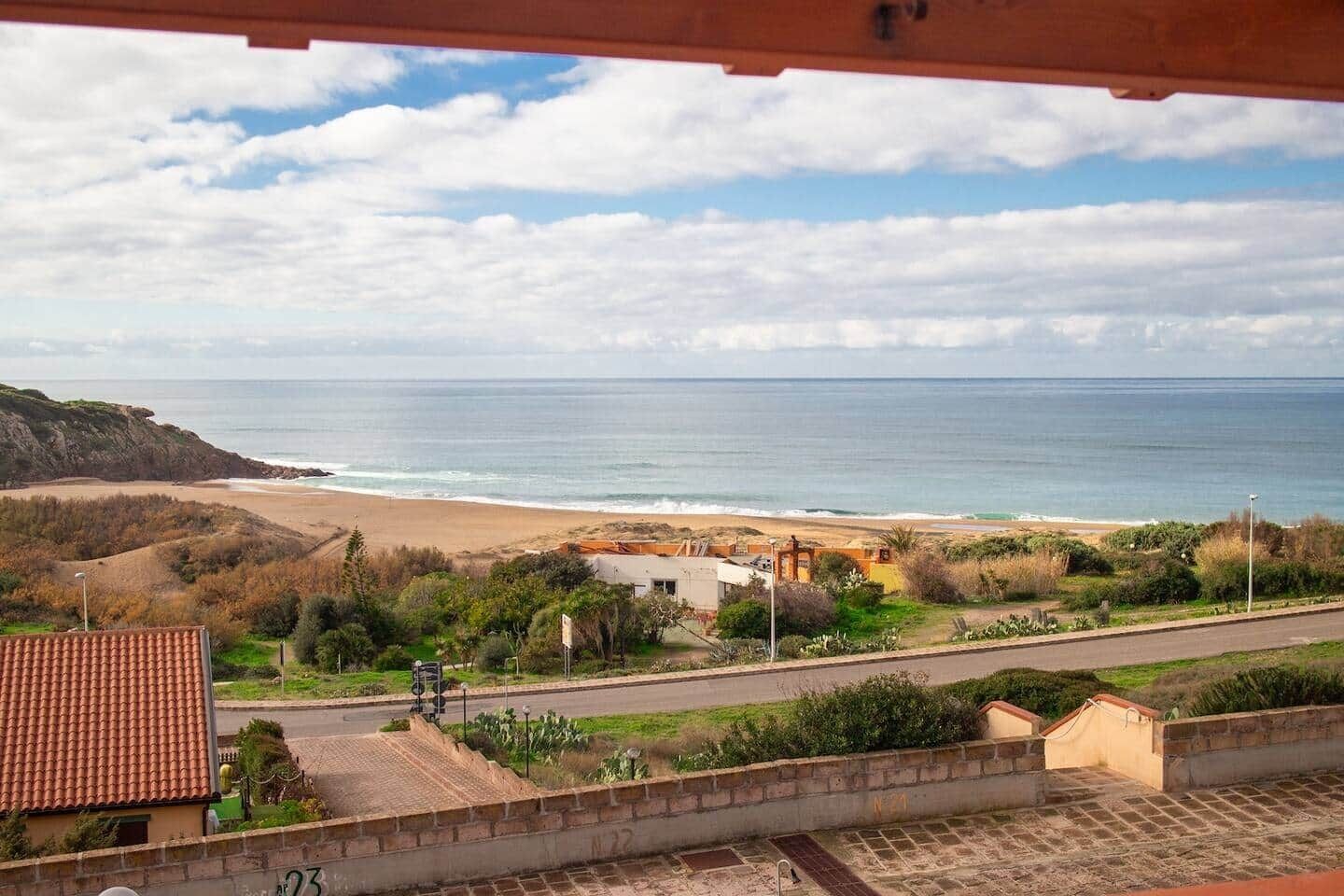 A coastal view with a beach, a road, and buildings in the foreground.