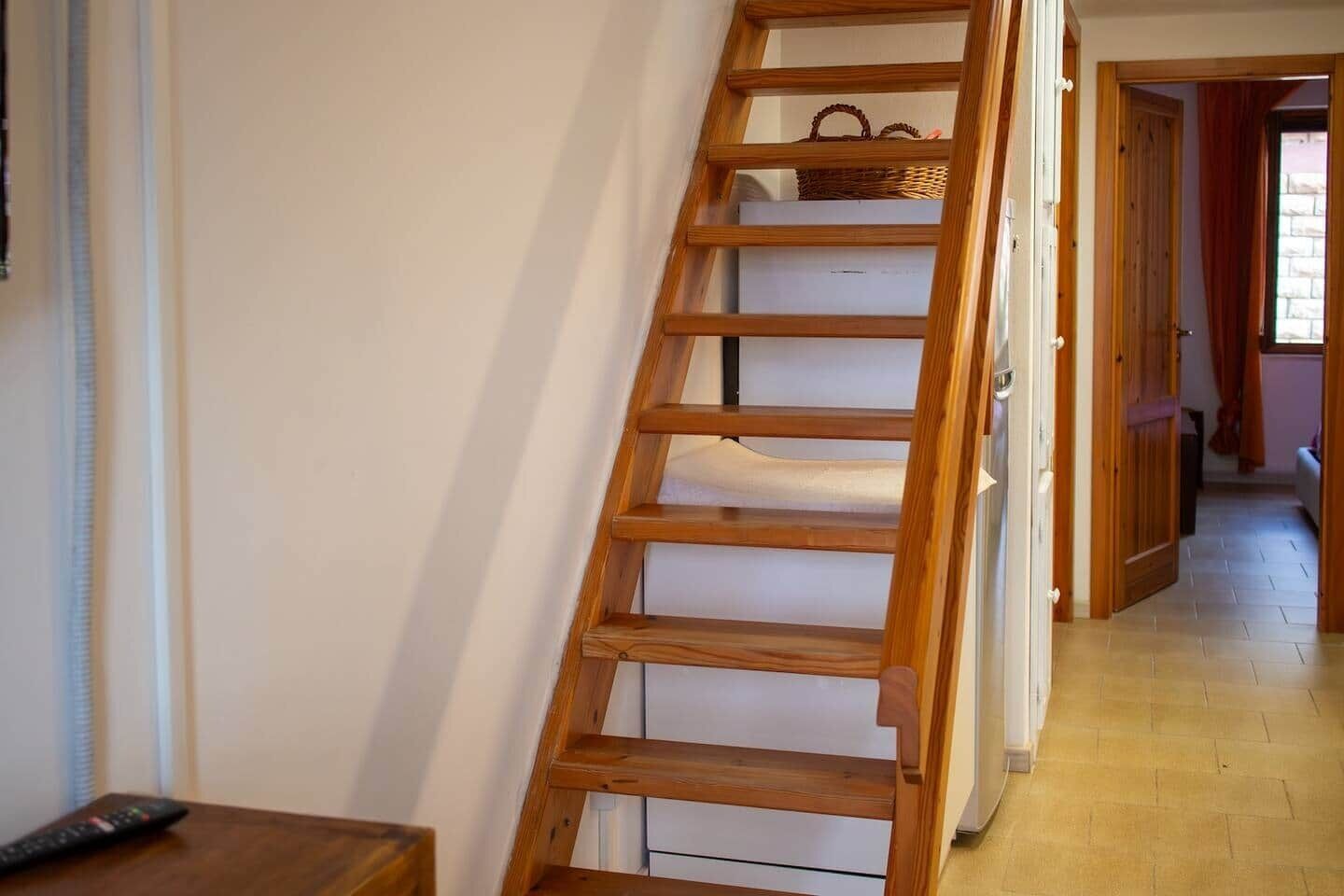 A wooden ladder leaning against a wall in a hallway with a tiled floor.