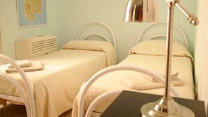 Ein Schlafzimmer mit zwei Betten, einem Schreibtisch, einer Lampe und einer Karte an der Wand.