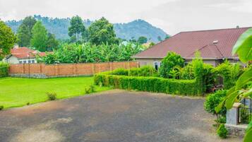 A residential area with a paved driveway, a well-maintained lawn, and a house with a red roof.