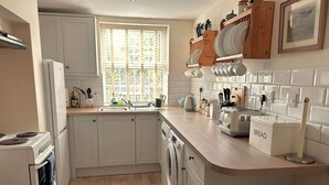 A modern kitchen with white cabinets, a built-in oven, a dishwasher, and a wooden countertop. - Traditional flint cottage, tucked away in the town of Wells-next-the-Sea (Wells-next-the-Sea)
