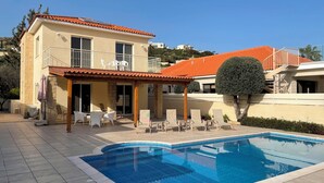 A two-story house with a swimming pool, outdoor seating, and a covered patio area.