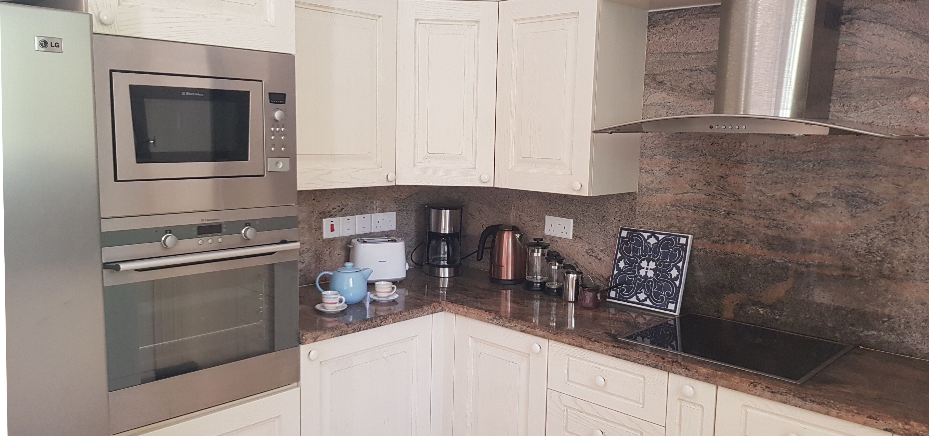 A modern kitchen with stainless steel appliances, white cabinetry, and a granite countertop.
