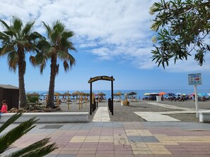 A beach entrance with a sign reading 'HAMACAS MANOLO', palm trees, beach umbrellas, and a clear sky. - Laguna Beach - Coral Coast (El Morche)