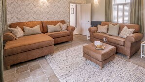 A living room with two brown sofas, a white rug, and a small table with a glass of wine. - Charming Grade II listed sanctuary tucked away in Wells-next-the-Sea (Wells-next-the-Sea,)