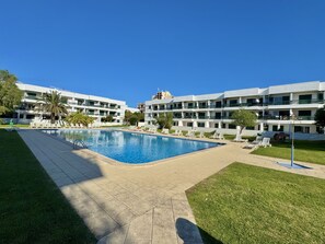 A hotel with a swimming pool surrounded by lounge chairs and palm trees. - Vilamoura Downtown by Homing (Loulé)