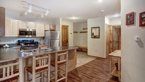 Eine moderne Küche mit Holzausstattung, Edelstahlgeräten und einer Theke mit Barhocker.