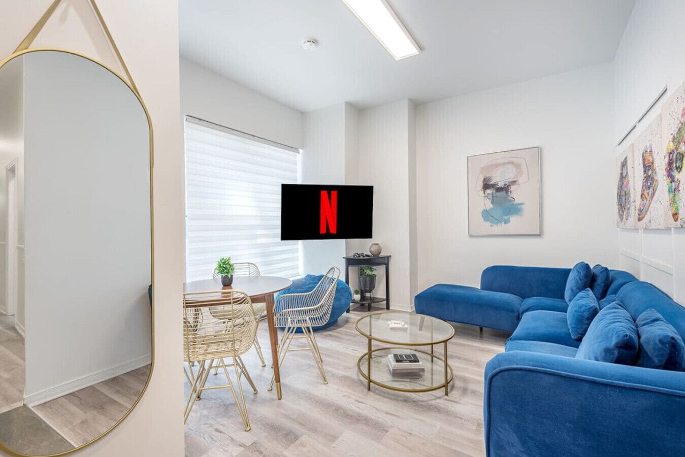 A modern living room with a blue sofa, a round coffee table, and a dining area with a small table and chairs.