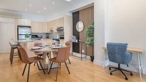 A modern kitchen with a dining area, a small office space, and a large window. - Charming Family Escape in Trendy Plateau Montreal (Montréal)