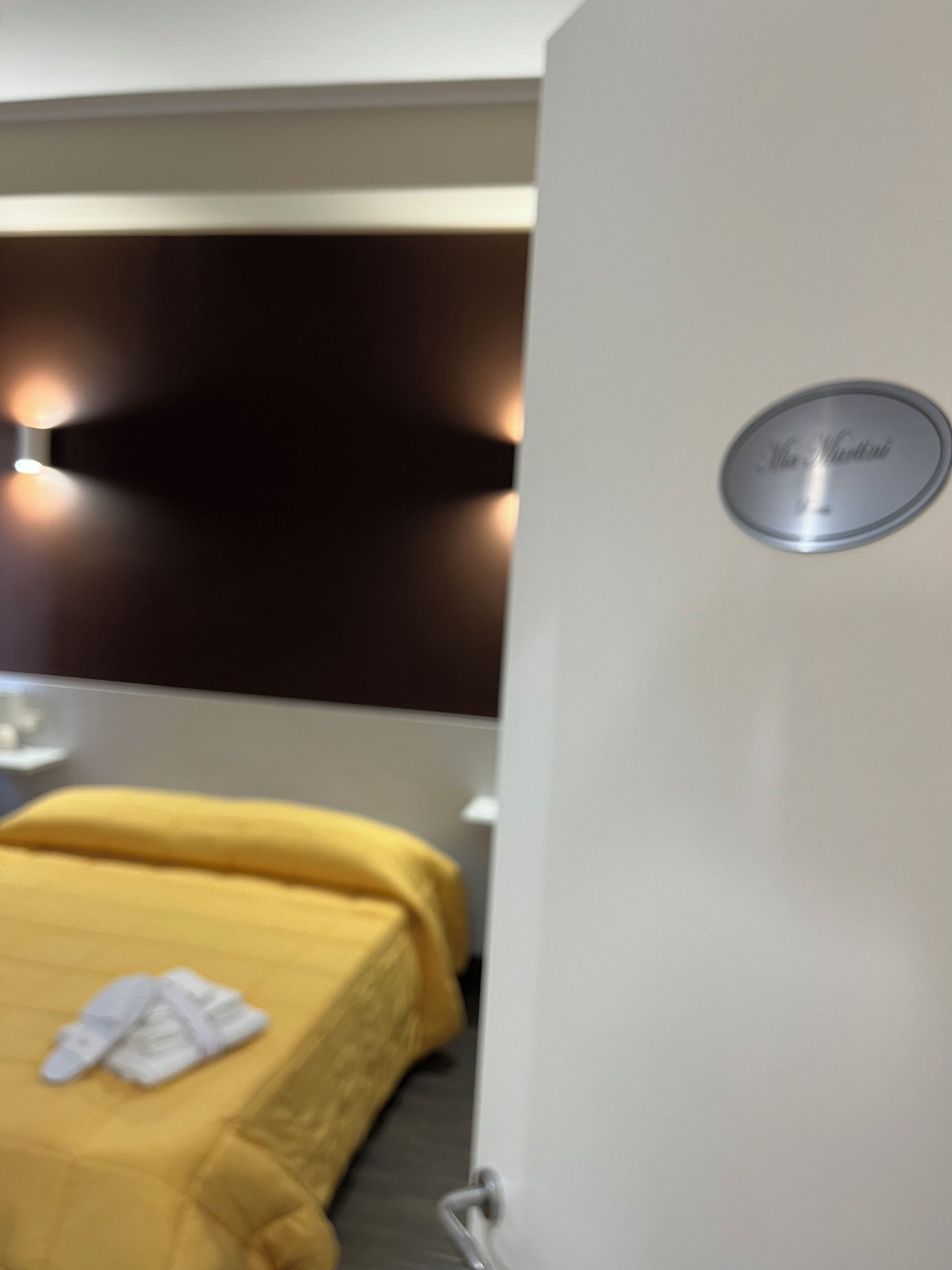 A hotel room with a bed, a nightstand, and a wall-mounted sign that reads "The Metropolitan."