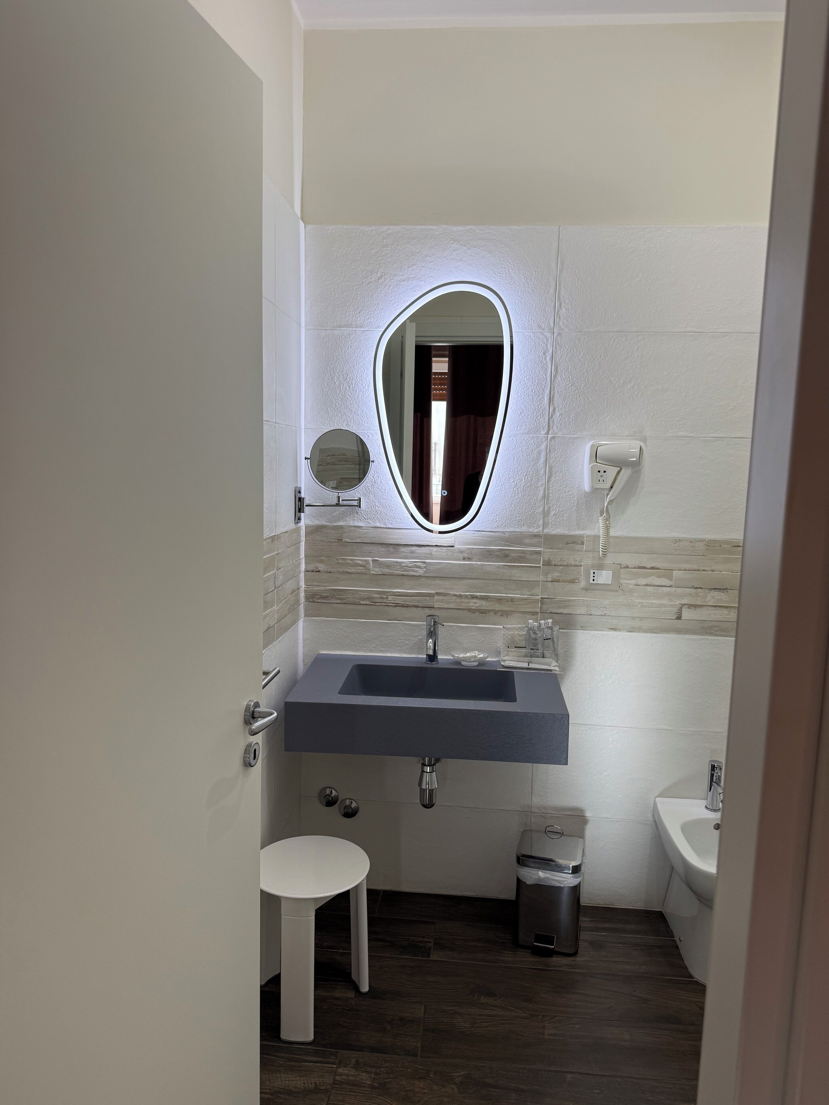 A bathroom with a vanity, sink, mirror, and toilet.