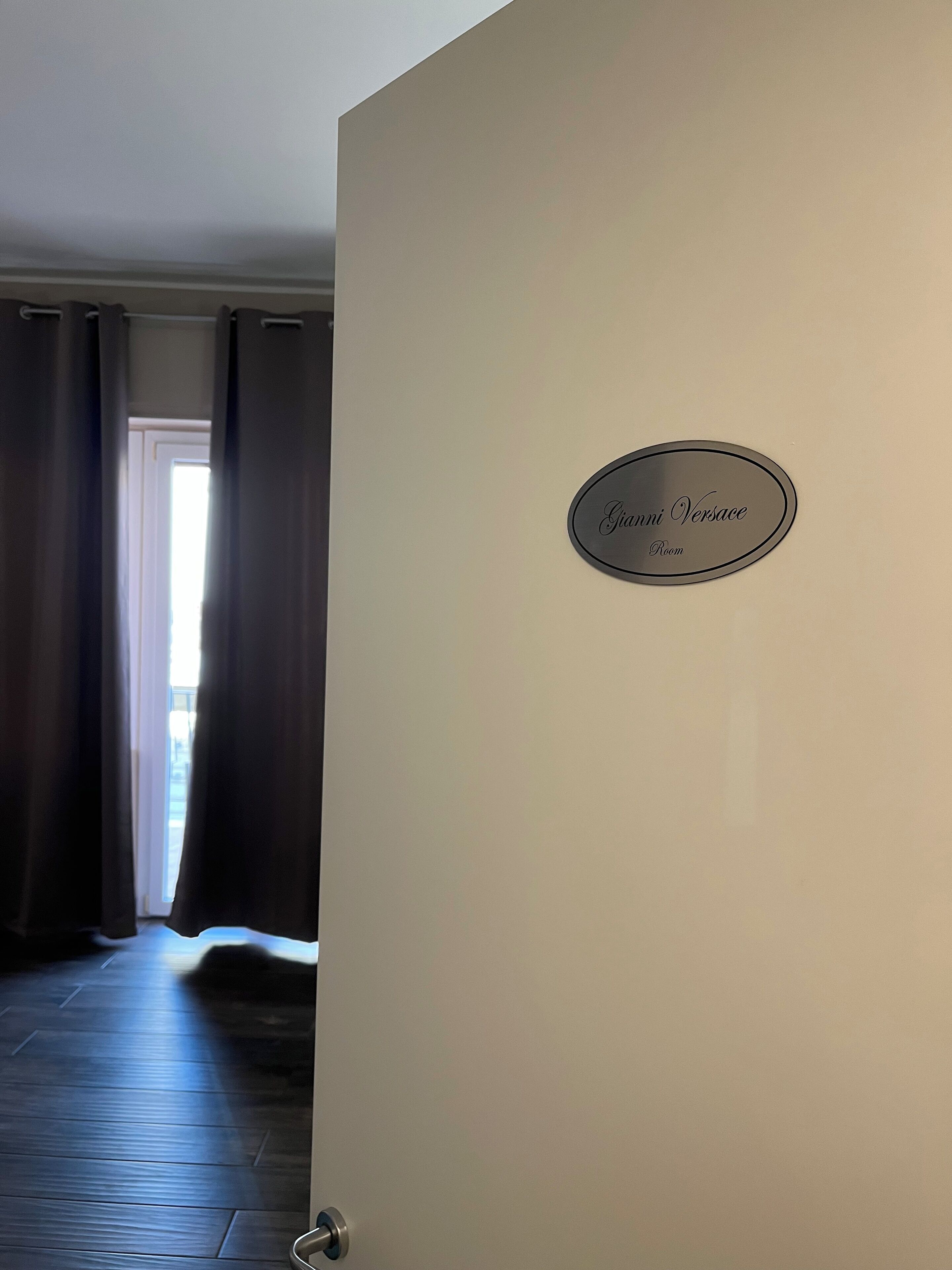 Een hotelkamer met een bordje met daarop 'Gianni Versace Room'.