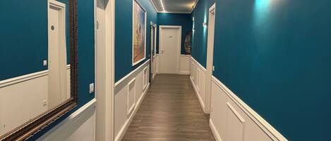 A hallway with teal walls, white trim, and wooden flooring.