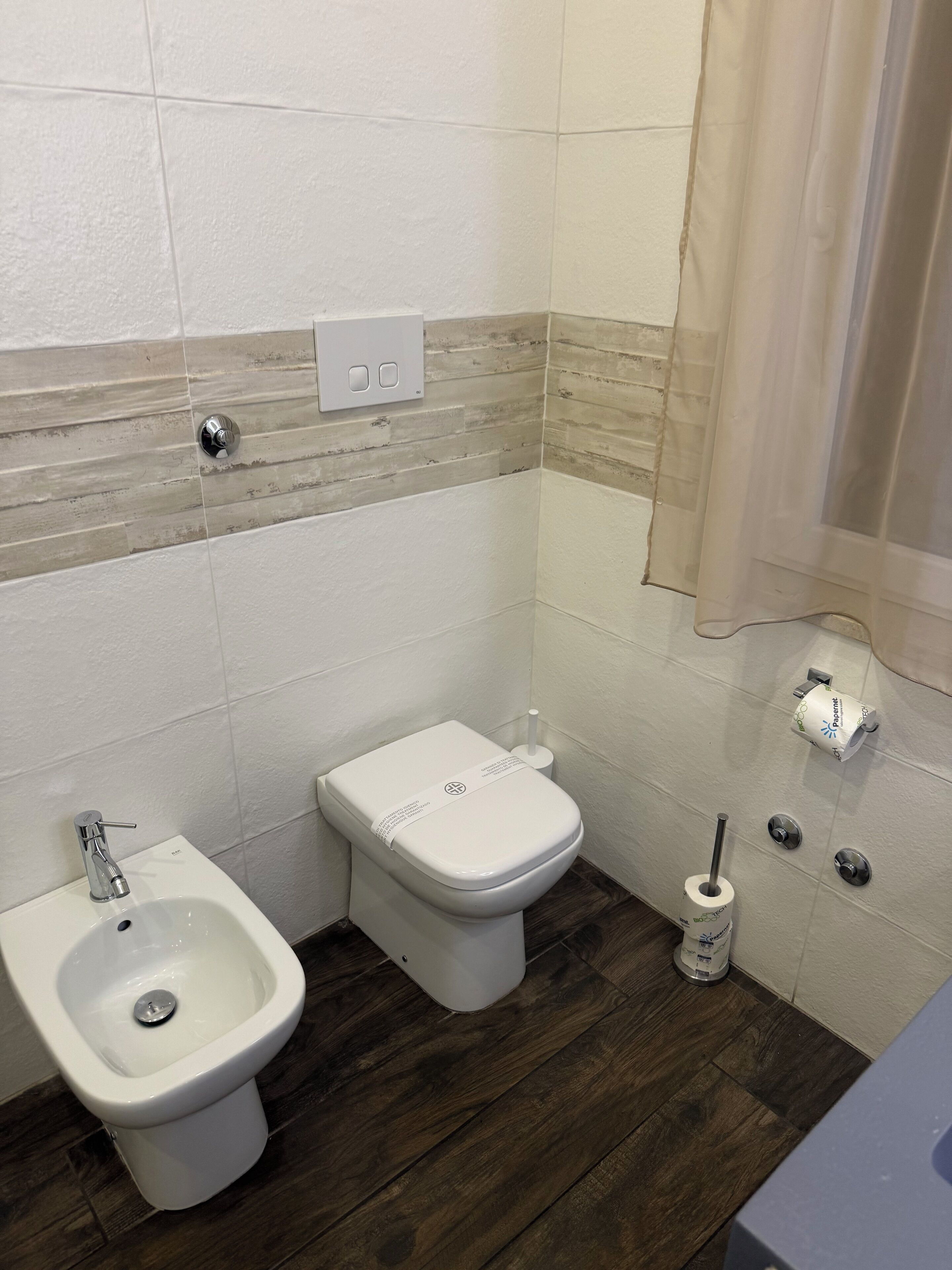 A bathroom with a bidet, toilet, and bidet seat.