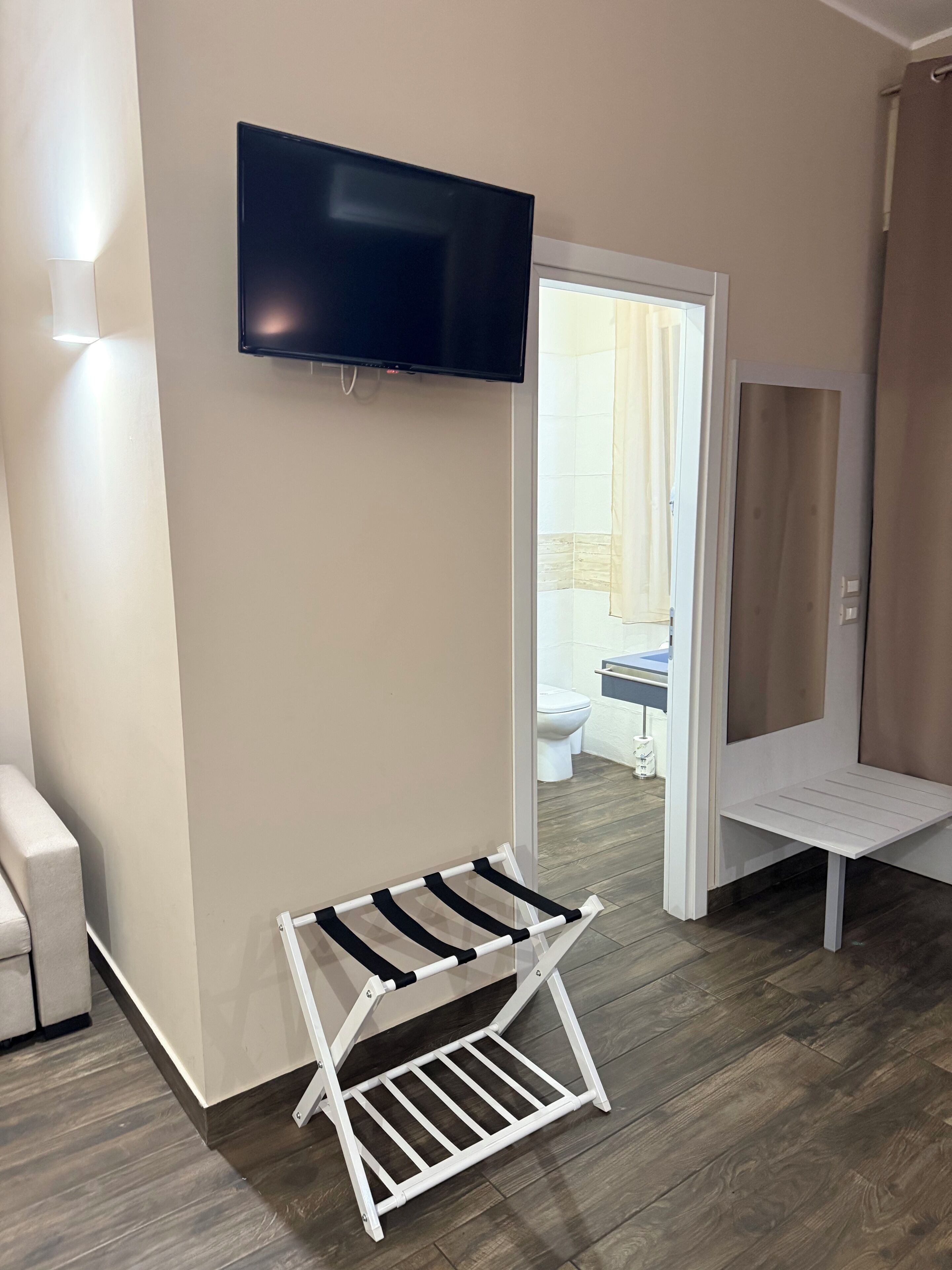 Una habitación moderna con un televisor de pantalla plana en la pared, un banco blanco y un tendedero a rayas negras y blancas.