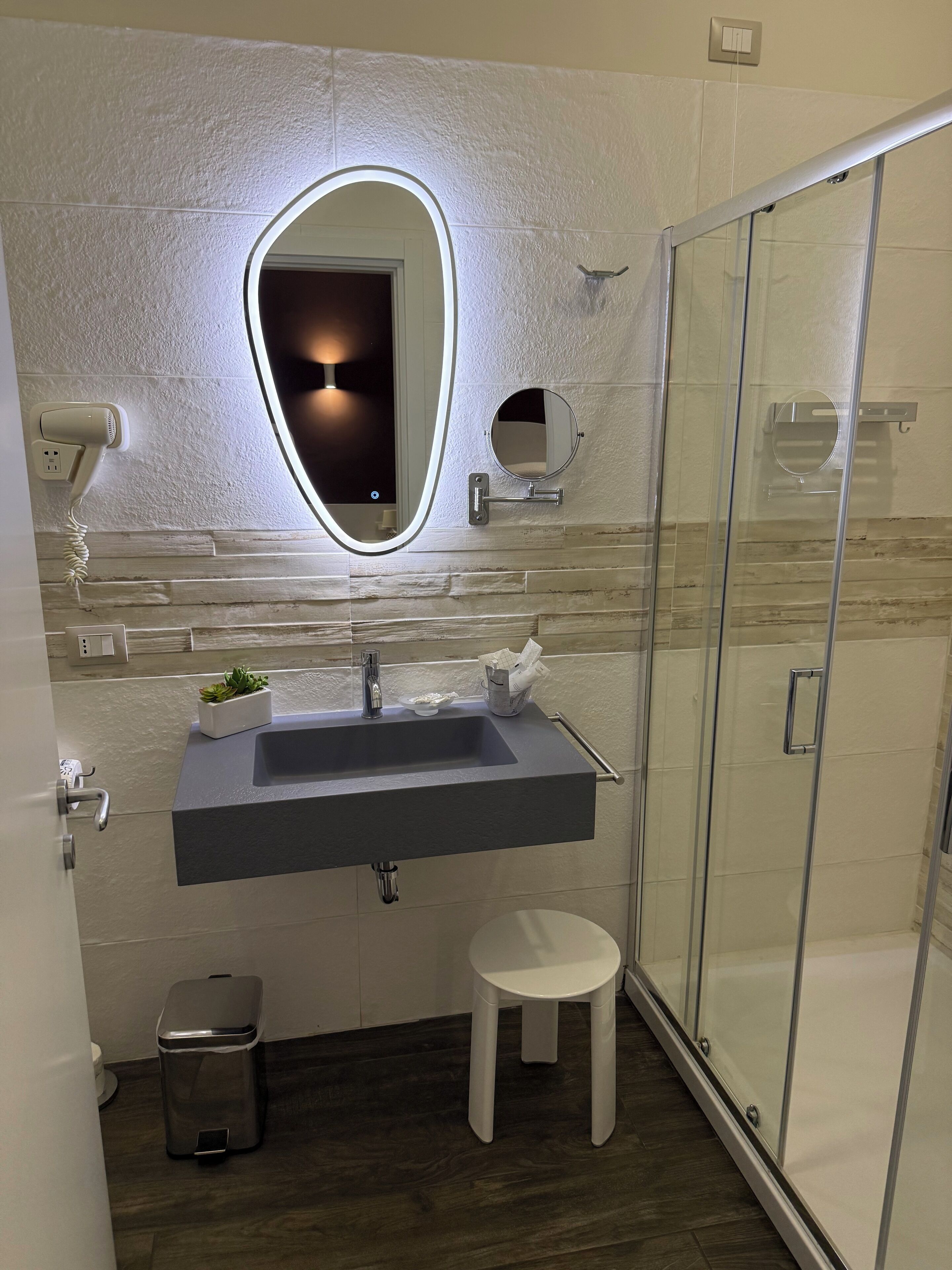 A modern bathroom with a large mirror, a built-in sink, and a glass shower enclosure.