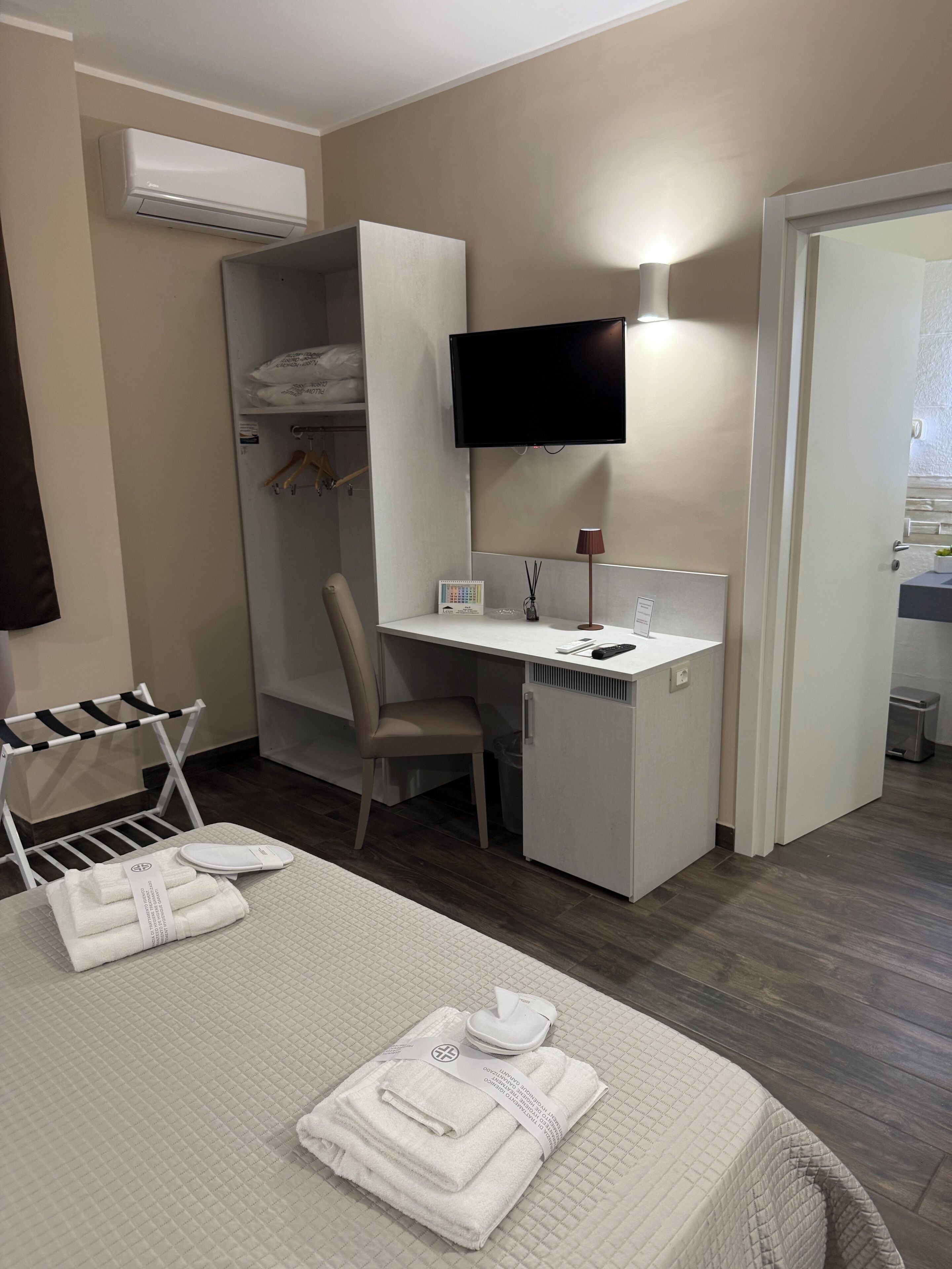 A hotel room with a bed, a desk, a TV, a wardrobe, and a bathroom.