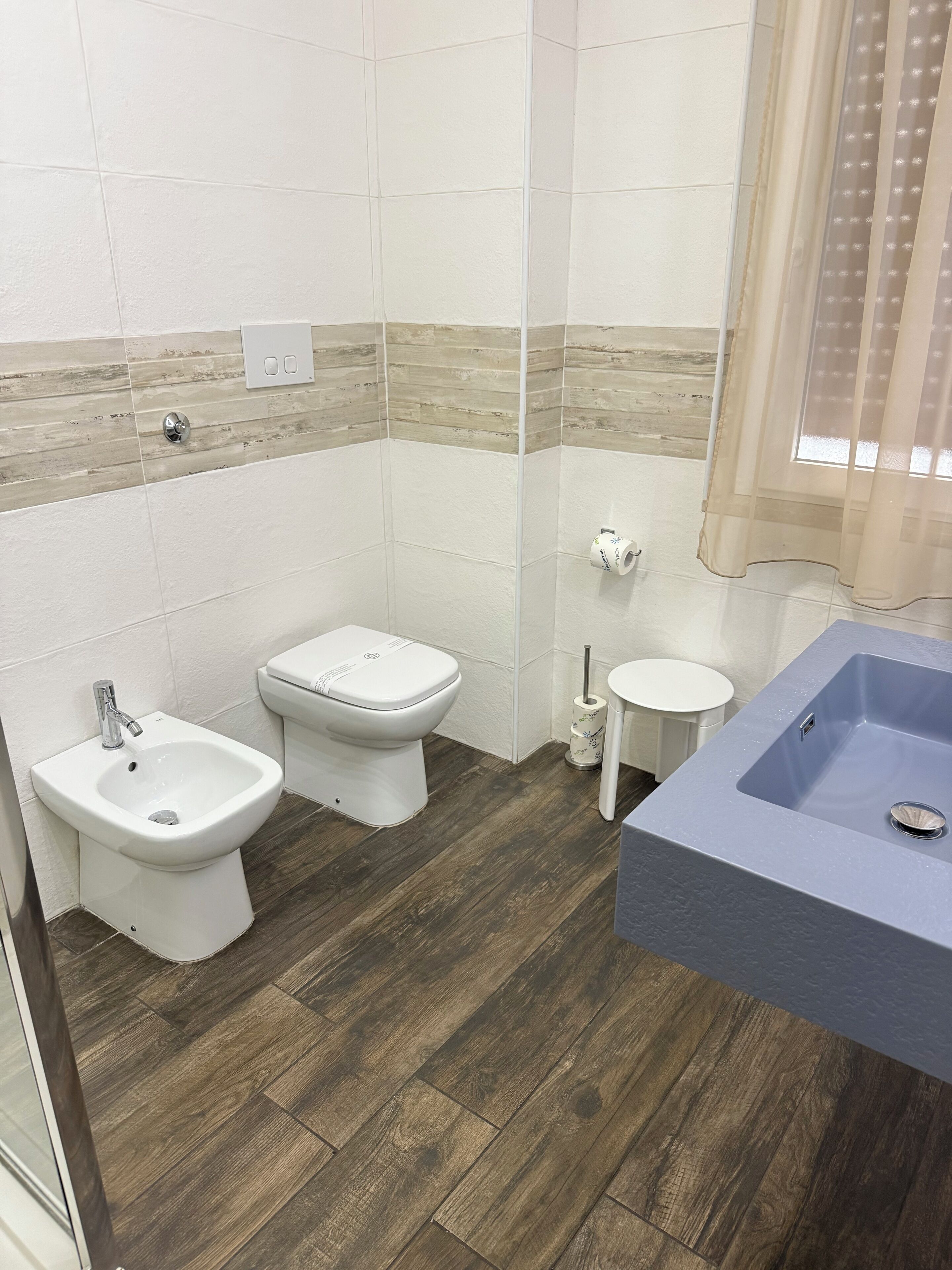 A bathroom with a bidet, toilet, and sink.