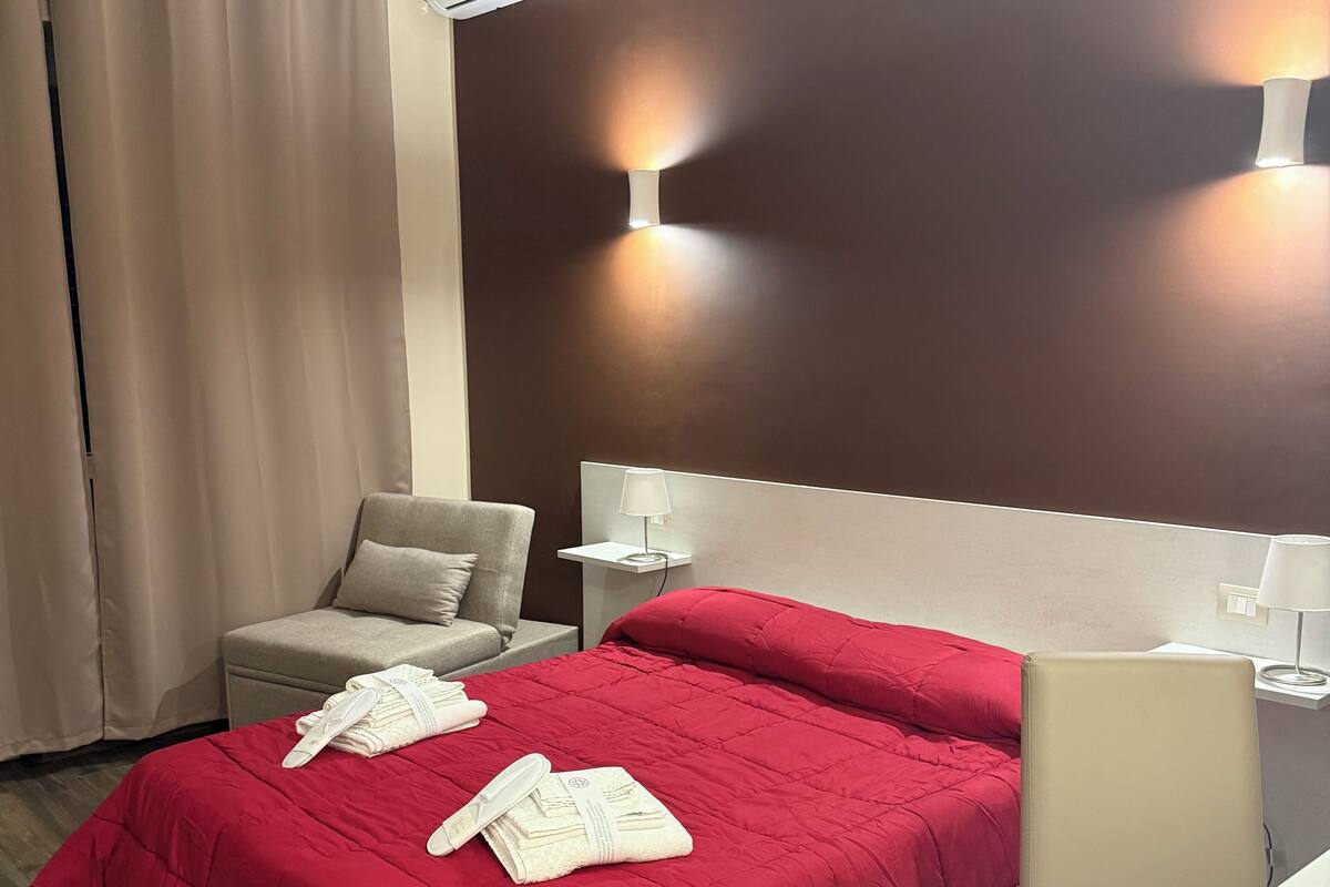 Una habitación de hotel con una cama, una silla, un escritorio y un equipo de aire acondicionado.