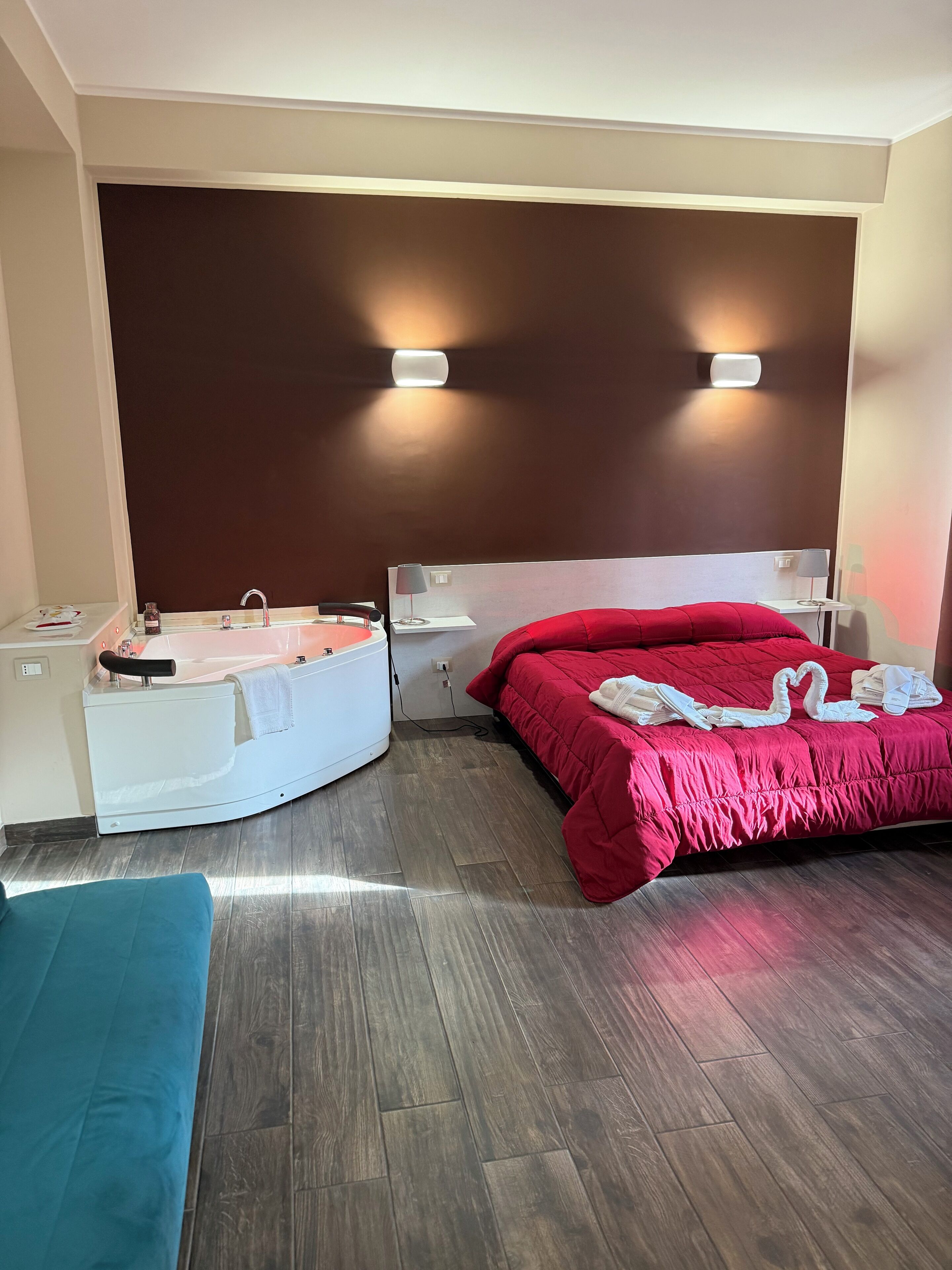 Een hotelkamer met een bed, een klein bureau, een stoel, een badkuip en een bankje.