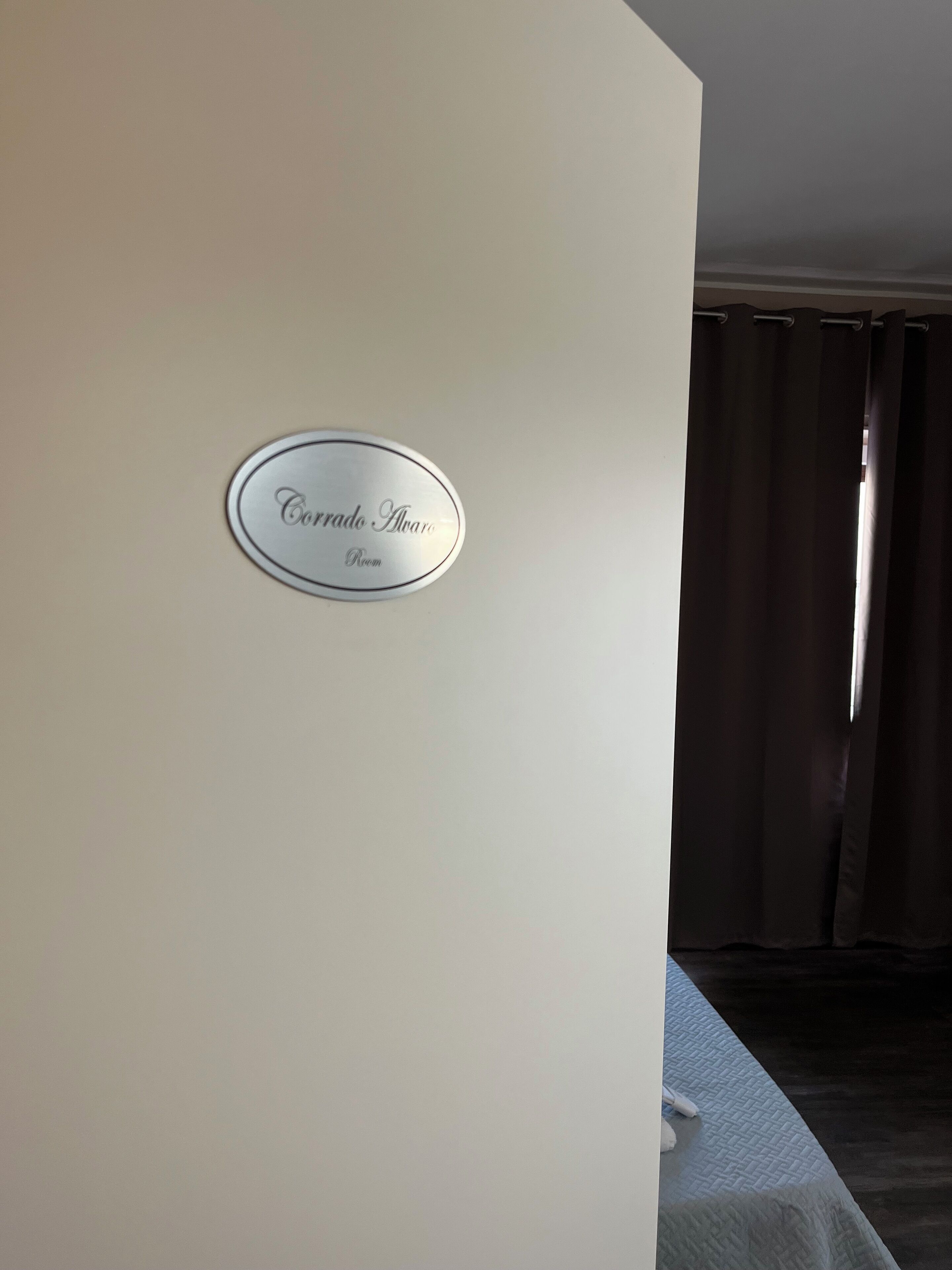 Une plaque sur un mur portant l’inscription « Salle Corrado Alvaro ».