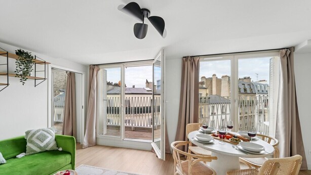 Een modern appartement met balkon, een eethoek met een tafel voor twee personen, en een groene bank.